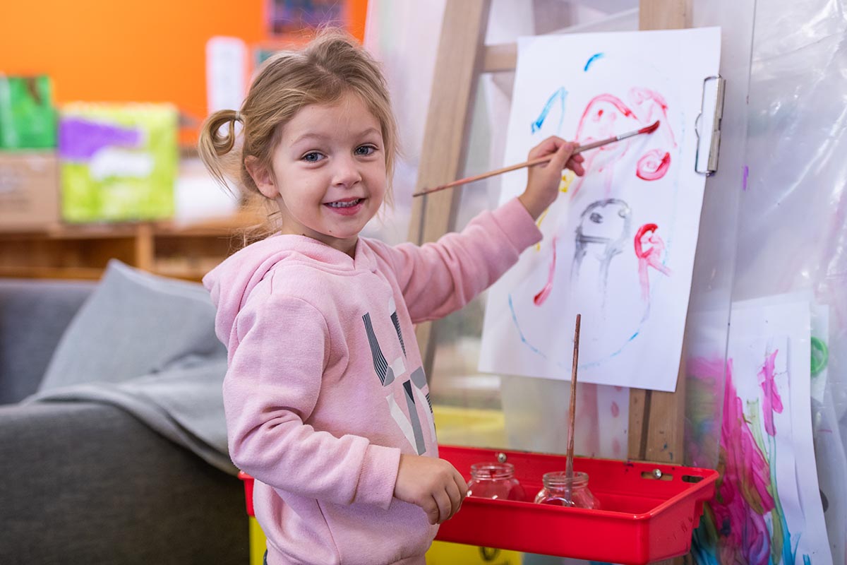 Young girl painting a picture on a canvas